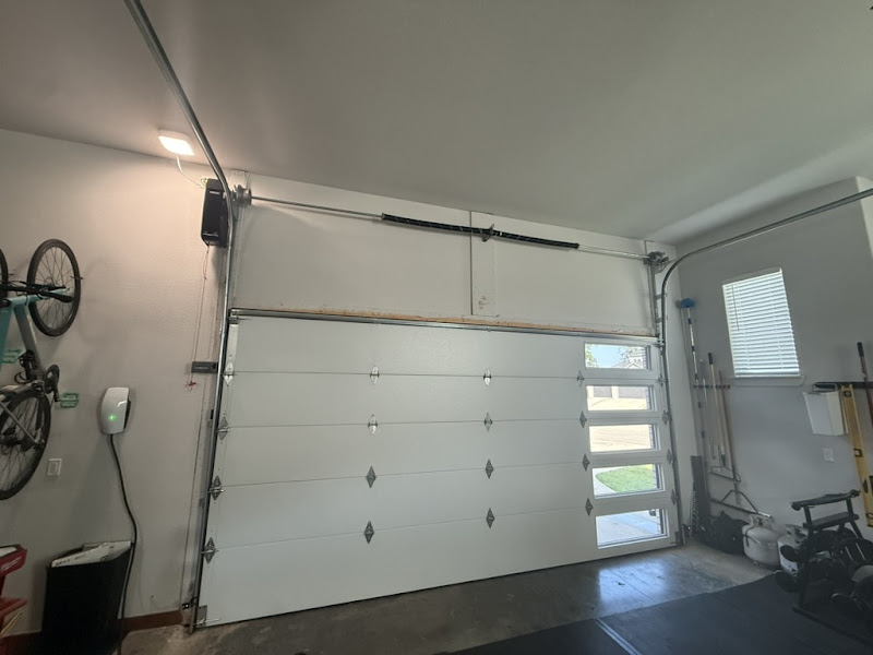 Elite Garage Door Services of Northwest ArkansasA clean, white residential garage door inside a garage, with visible overhead tracks and garage door springs. The setting suggests a reliable garage door service in Northwest Arkansas, emphasizing local expertise and professionalism.