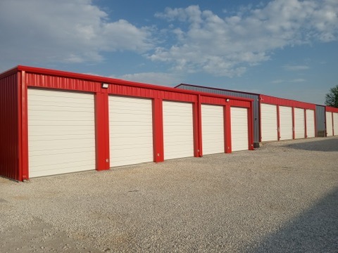 Elite Garage Door Services of Northwest ArkansasA row of red and white commercial storage units under a blue sky, showcasing overhead garage doors in Northwest Arkansas, highlighting local, professional garage door service for reliability and safety.