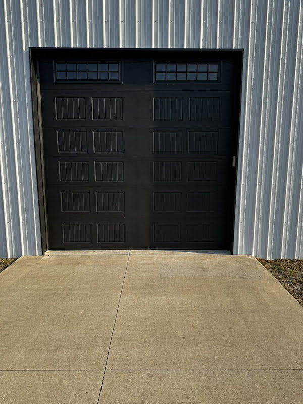 Elite Garage Door Services of Northwest ArkansasA black residential garage door with windowed panels is installed on a metal building in Northwest Arkansas, reflecting Elite Garage Door's professional and reliable service in Rogers AR and surrounding areas.