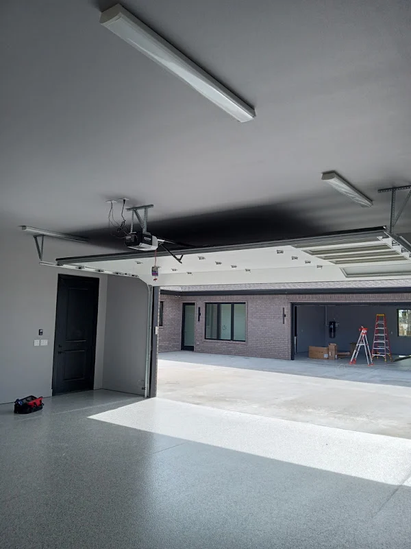 Elite Garage Door Services of Northwest ArkansasA spacious garage with a partially open overhead garage door, showcasing a modern interior. A toolbox is on the floor, suggesting ongoing professional garage door service. This scene is in Northwest Arkansas, emphasizing local expertise.