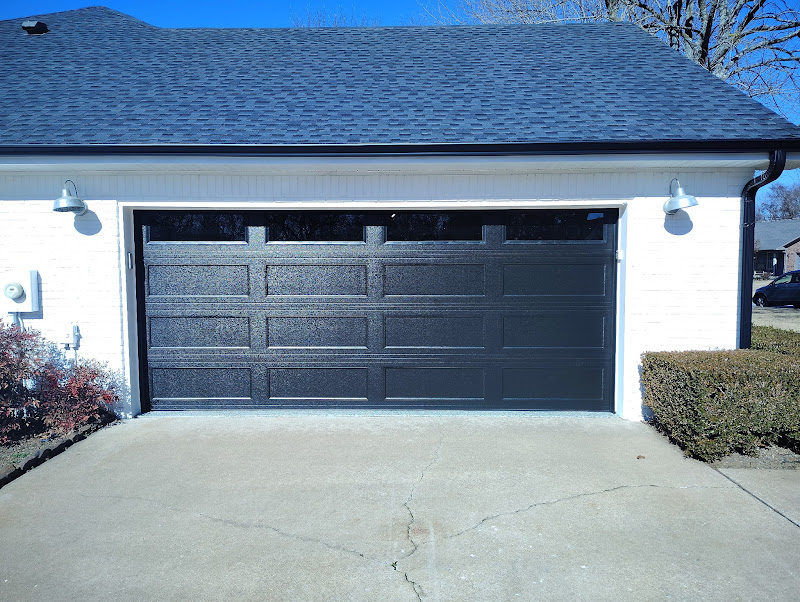 Elite Garage Door Services of Northwest ArkansasA modern black residential garage door is installed on a white brick house, showcasing the sleek design typical of professional garage door installation services in Northwest Arkansas.