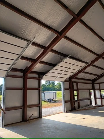 5423BE27 45BD 48D5 9359 D30CD07B3E40 4 5005 c Elite Garage Door Services of Northwest ArkansasInterior view of a large building with overhead garage doors partially open, showing a sunny outdoor scene. This setup highlights the need for reliable garage door service in Northwest Arkansas, ensuring functionality and ease of access.
