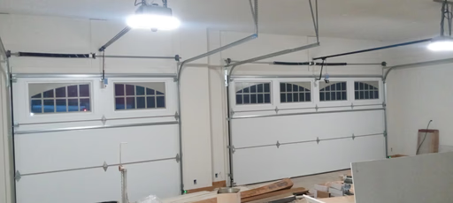 Elite Garage Door Services of Northwest ArkansasA well-lit garage interior in Rogers AR shows two newly installed white overhead garage doors, highlighting a recent professional garage door installation by a local service in Northwest Arkansas.