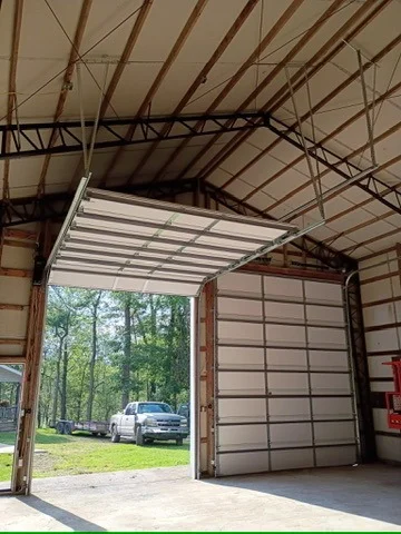Elite Garage Door Services of Northwest ArkansasIn a spacious garage, an overhead garage door is partially open, revealing a sunny view of trees and a parked truck outside, highlighting a reliable garage door service in Northwest Arkansas.