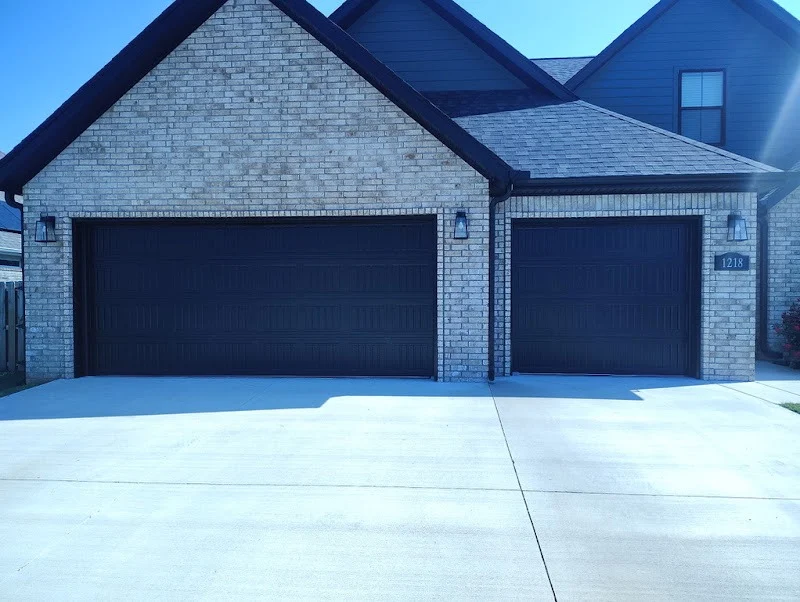 Elite Garage Door Services of Northwest ArkansasA modern home with two large, dark-colored residential garage doors in Northwest Arkansas, highlighting the need for reliable garage door service and installation.