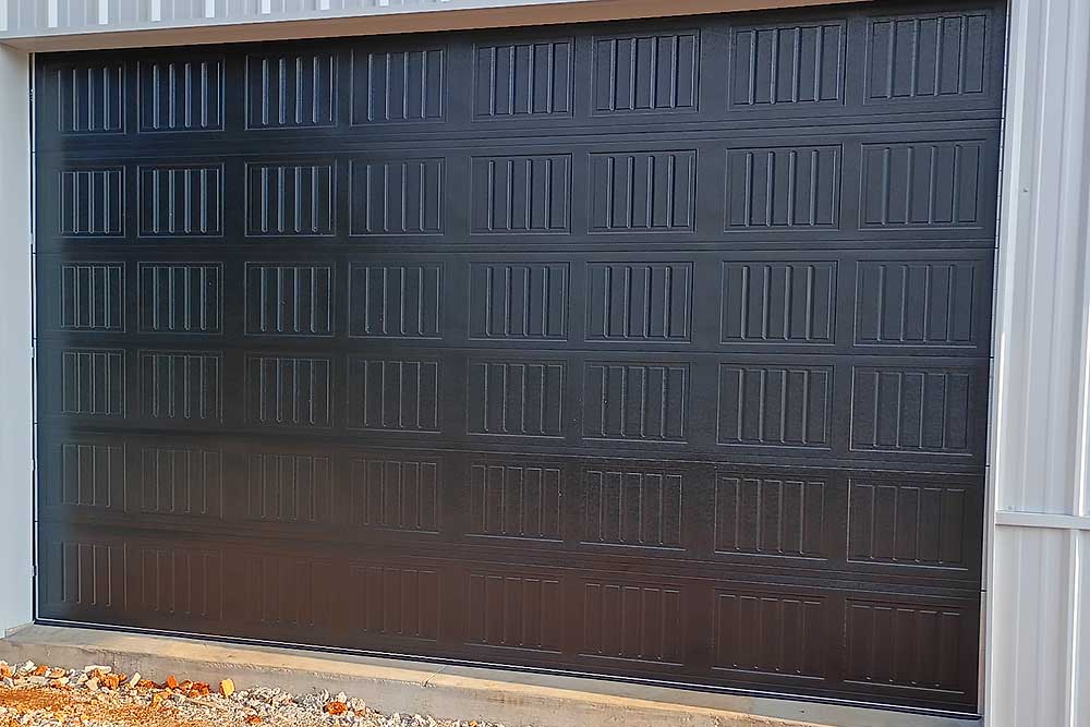 Centerton-image Elite Garage Door Services of Northwest Arkansas-A newly installed black residential garage door in Northwest Arkansas, showcasing sleek panels and modern design, highlighting professional garage door installation services available in the local area.