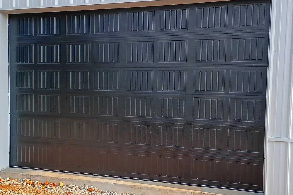 Elite Garage Door Services of Northwest Arkansas-A newly installed black residential garage door in Northwest Arkansas, showcasing sleek panels and modern design, highlighting professional garage door installation services available in the local area.