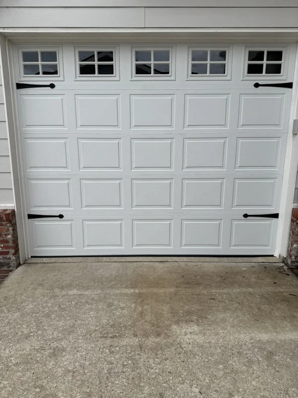 Elite Garage Door Services of Northwest ArkansasA freshly installed white residential garage door with decorative windows is shown, highlighting Elite Garage Door's professional garage door installation service in Northwest Arkansas.