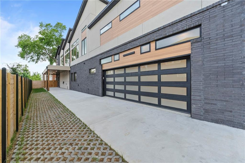 Elite Garage Door Services of Northwest ArkansasModern residential home with sleek black and wood overhead garage doors, showcasing a recent garage door installation. The setting is a sunny day in Northwest Arkansas, highlighting the local, professional garage door service.