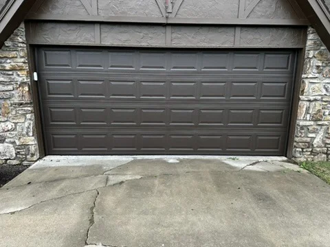 Elite Garage Door Services of Northwest ArkansasA brown residential garage door is closed against a stone exterior. The scene highlights the professional garage door installation in Northwest Arkansas, showcasing reliability and quality for homeowners in areas like Rogers AR and Fayetteville AR.