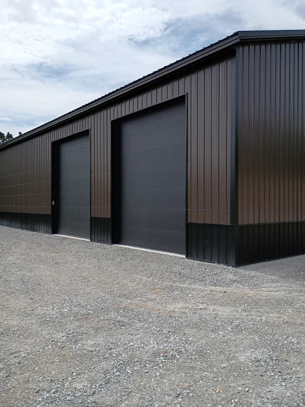 Elite Garage Door Services of Northwest ArkansasA large, black metal building with multiple overhead garage doors is shown on a gravel lot, illustrating the need for reliable garage door service in Northwest Arkansas.