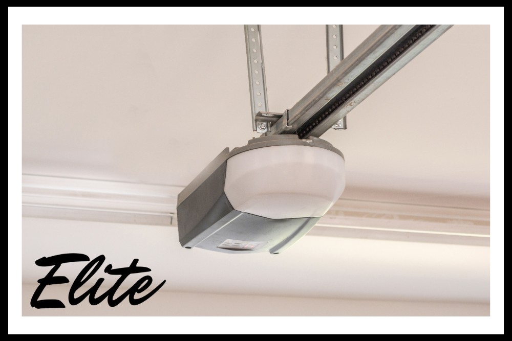Garage Door Replacement vs Repair-2 Elite Garage Door Services of Northwest Arkansas-A gray and white garage door opener is mounted on the ceiling, representing reliable garage door service in Northwest Arkansas. The Elite logo is visible, emphasizing local expertise in garage door openers and installations.