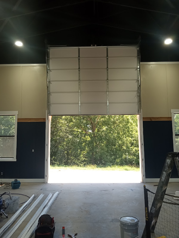 Elite Garage Door Services of Northwest ArkansasAn overhead garage door installation is underway in a spacious room with tools and materials scattered on the floor. Sunlight filters through the open door,…