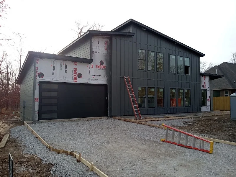 Elite Garage Door Services of Northwest ArkansasA modern house under construction in Northwest Arkansas features a newly installed black overhead garage door. A ladder leans against the house, indicating ongoing work.…
