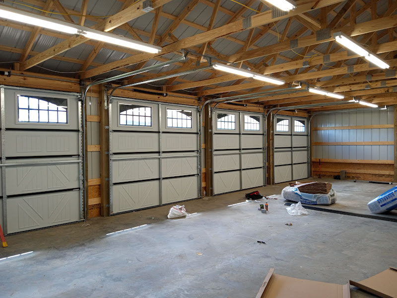 Elite Garage Door Services of Northwest ArkansasA spacious garage interior in Northwest Arkansas features four newly installed white overhead garage doors with windows, ready for professional garage door service. The well-lit…