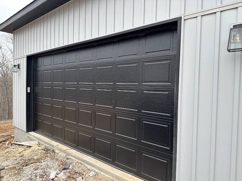 Elite Garage Door Services of Northwest ArkansasA newly installed black residential garage door on a gray building in Northwest Arkansas, showcasing local, reliable garage door service.