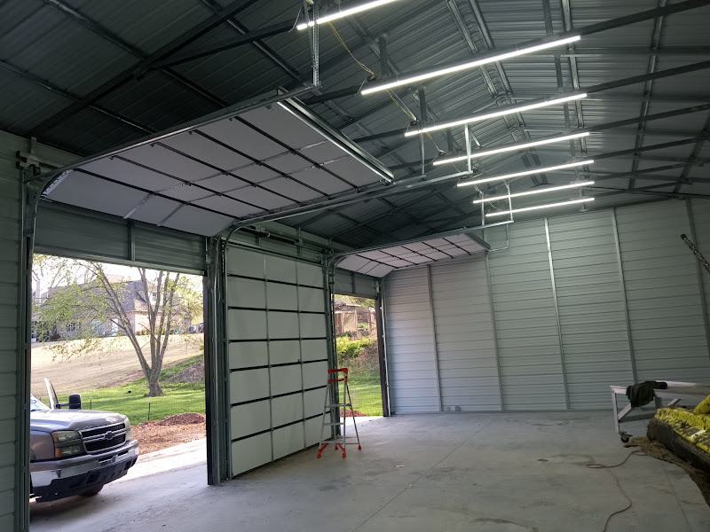 Elite Garage Door Services of Northwest ArkansasAn open garage with overhead doors being installed in a spacious interior, showing a ladder and a parked truck outside. This setting highlights professional garage door installation in Northwest Arkansas with reliable service.