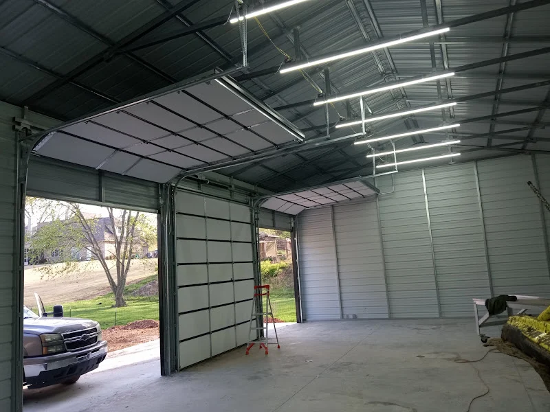 Elite Garage Door Services of Northwest ArkansasAn open garage with overhead doors being installed in a spacious interior, showing a ladder and a parked truck outside. This setting highlights professional garage door installation in Northwest Arkansas with reliable service.