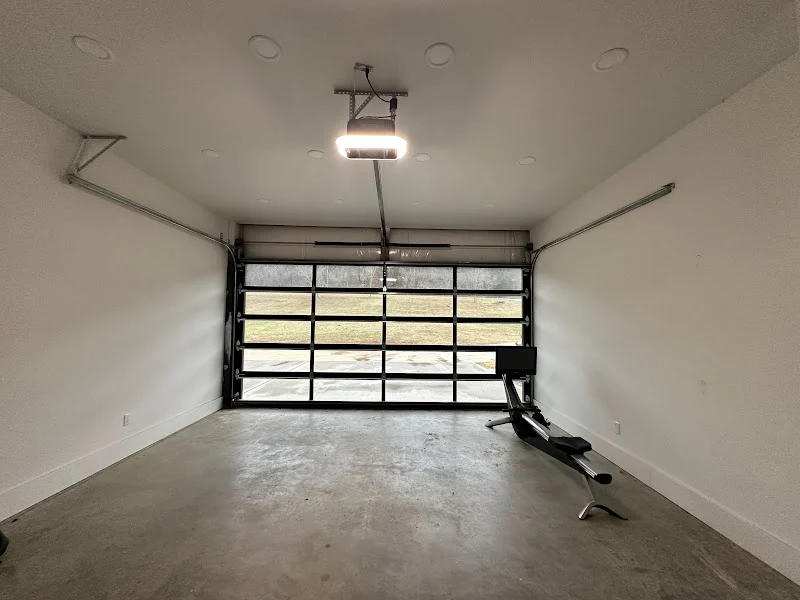 Elite Garage Door Services of Northwest ArkansasAn empty garage with modern overhead garage doors and a rowing machine inside, highlighting a clean, spacious area. The image underscores the professional garage door service available in Northwest Arkansas.