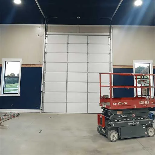 Elite Garage Door Services of Northwest Arkansas-An overhead garage door installation in progress inside a spacious garage, with a red lift platform positioned nearby. This setup highlights professional garage door service in Northwest Arkansas.