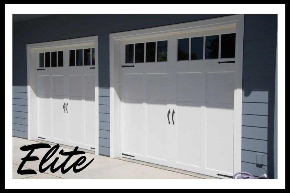 The Complete Guide to Garage Door Springs and How to Care for Them-2 Elite Garage Door Services of Northwest Arkansas-A pair of white residential garage doors with upper glass panels on a blue house in Northwest Arkansas, showcasing a recent professional garage door installation by Elite Garage Door.