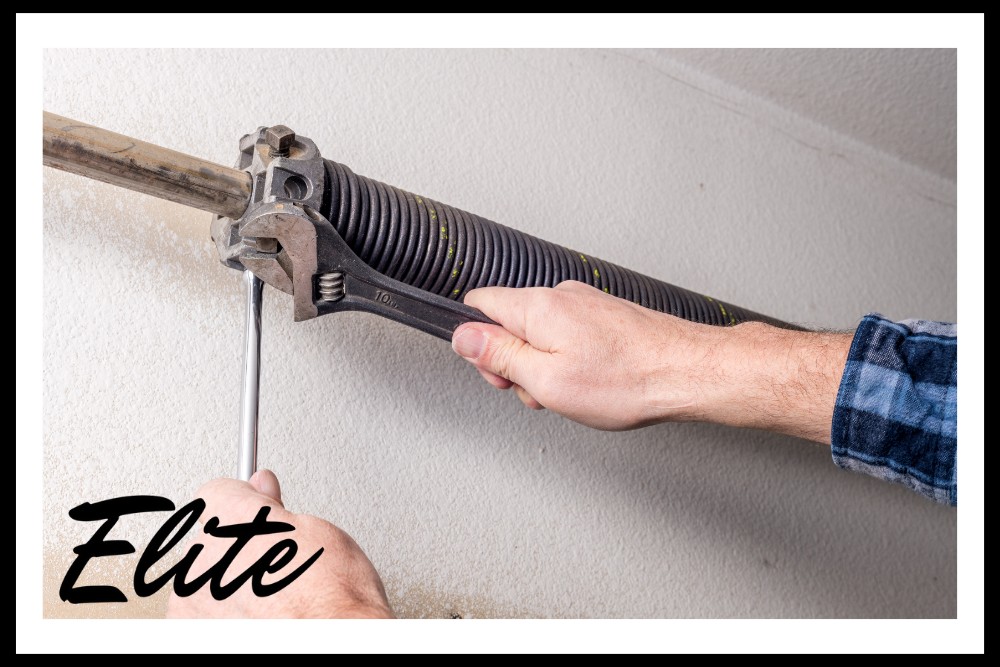 The Complete Guide to Garage Door Springs and How to Care for Them-3 Elite Garage Door Services of Northwest Arkansas-A professional technician in Northwest Arkansas is adjusting garage door springs with a wrench, showcasing reliable garage door repair services by Elite Garage Door.