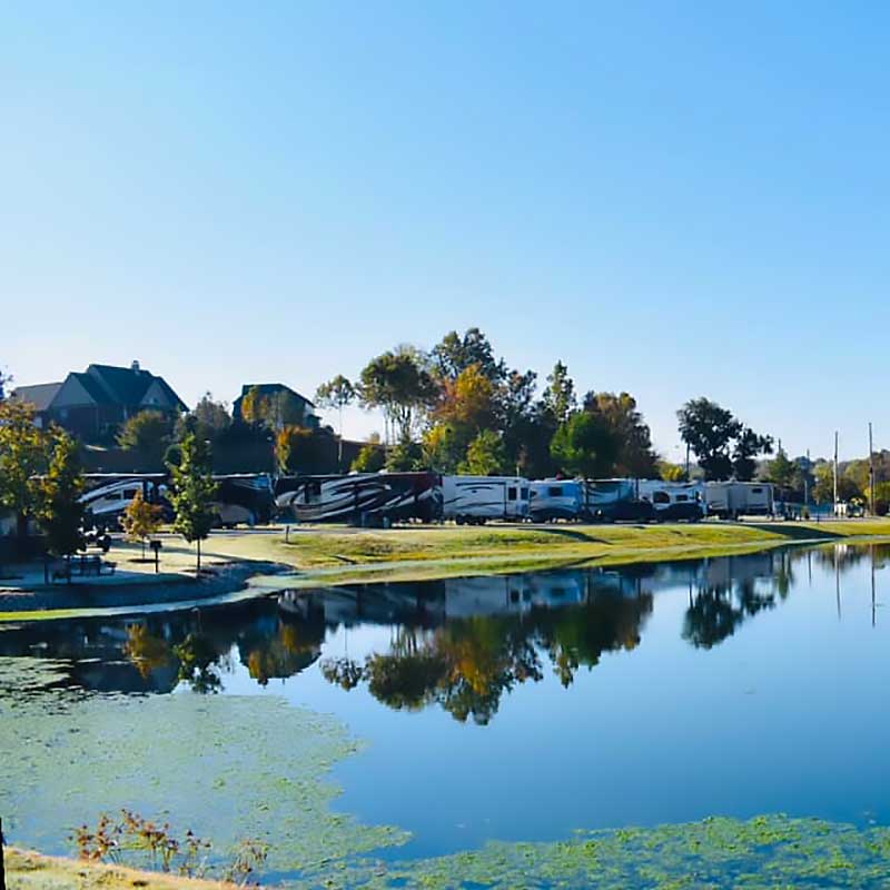Elite Garage Door Services of Northwest Arkansas-A serene lakeside scene in Northwest Arkansas with RVs parked along the shore, reflecting in clear blue water. This peaceful setting emphasizes the local community, ideal for homeowners seeking reliable garage door service in NWA.