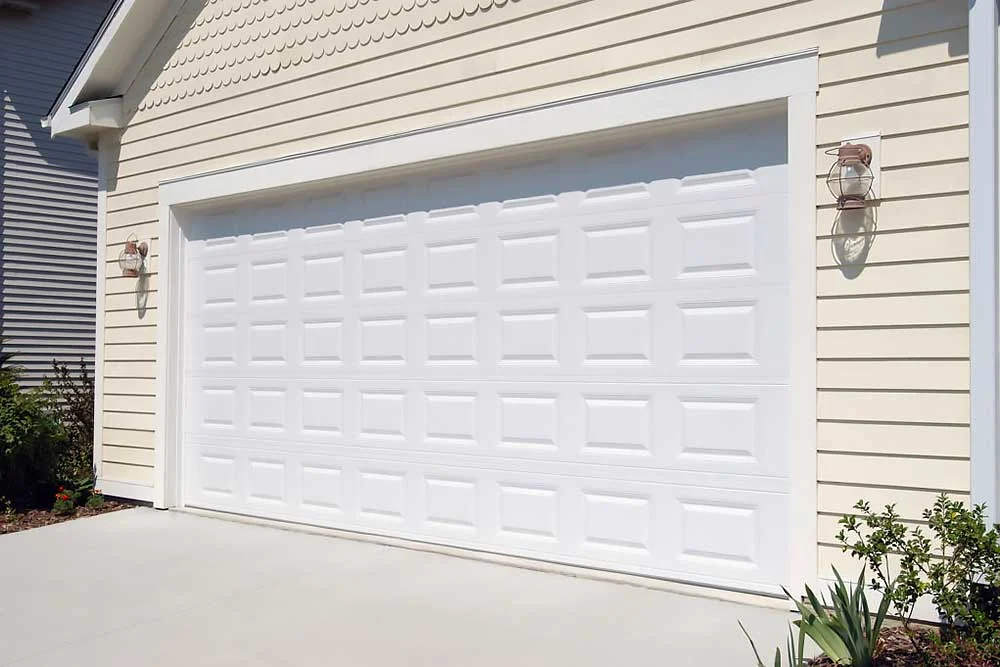 fayetteville-image Elite Garage Door Services of Northwest Arkansas-A newly installed white residential garage door in Northwest Arkansas is shown against a light yellow siding, highlighting local, reliable garage door service.