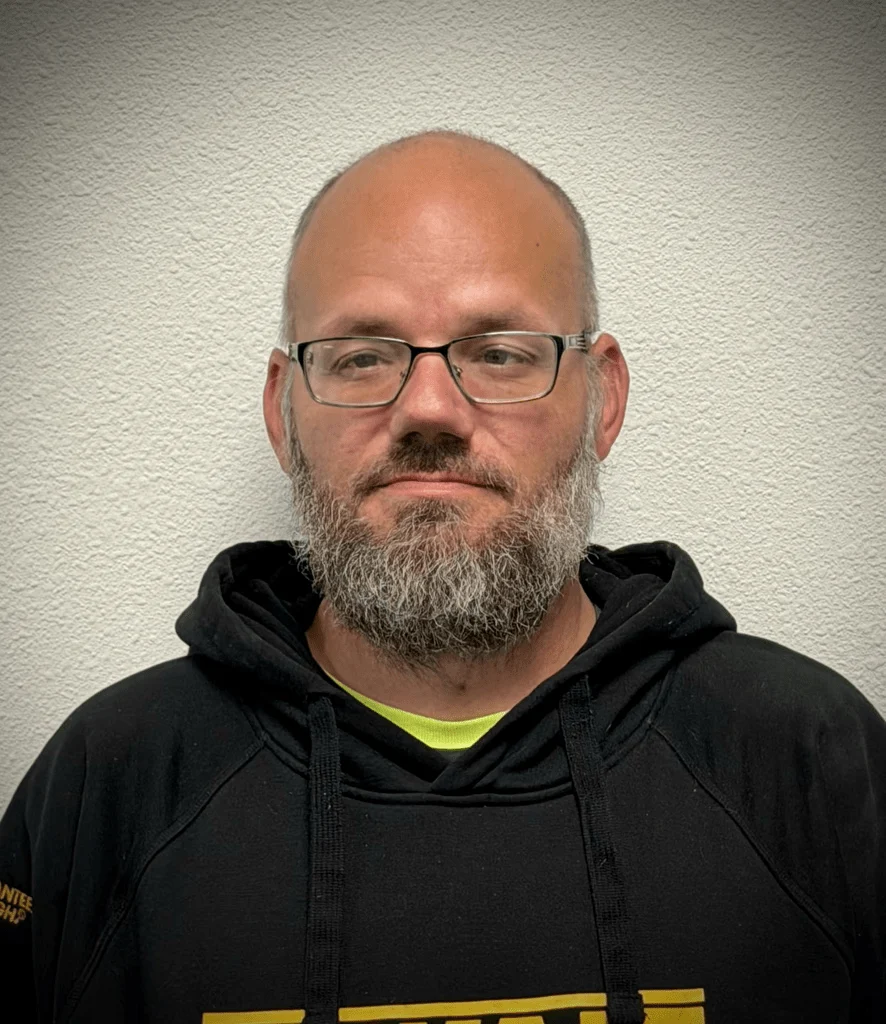 Elite Garage Door Services of Northwest ArkansasA professional technician in a black hoodie stands against a white wall, ready to provide reliable garage door repair services in Northwest Arkansas.