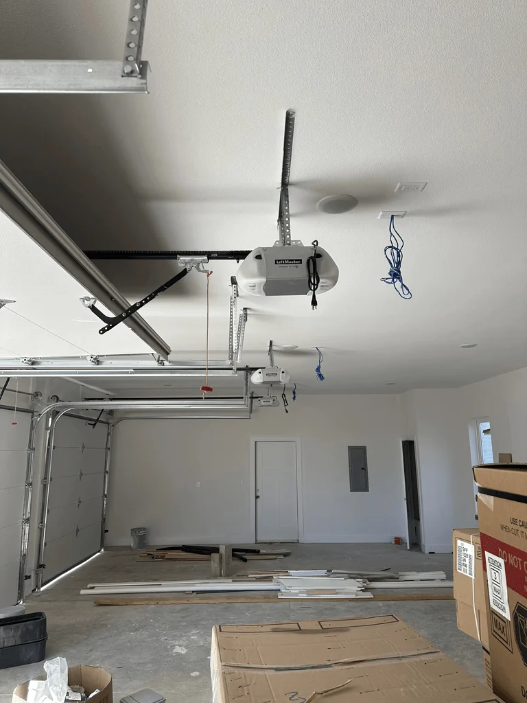 Elite Garage Door Services of Northwest ArkansasA partially installed garage with overhead garage doors and openers visible, along with scattered tools and materials, showcasing a professional garage door installation in progress in Northwest Arkansas.