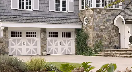 Elite Garage Door Services of Northwest ArkansasA charming stone and shingle house in Northwest Arkansas features two white residential garage doors. This image represents local, reliable garage door installation services aimed at enhancing home aesthetics and functionality.