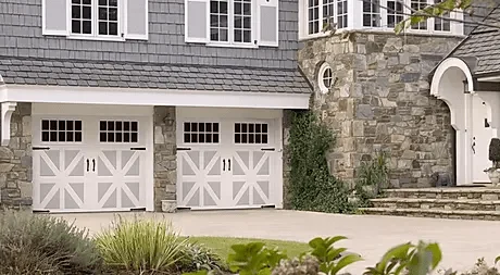 Elite Garage Door Services of Northwest ArkansasA charming stone and shingle house in Northwest Arkansas features two white residential garage doors. This image represents local, reliable garage door installation services aimed at enhancing home aesthetics and functionality.