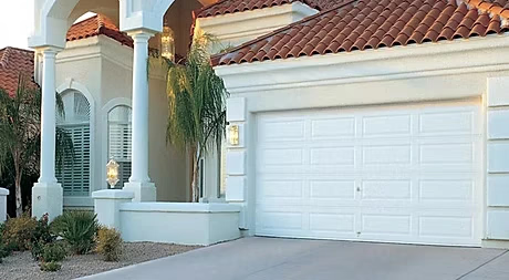 Elite Garage Door Services of Northwest ArkansasA white residential garage door is closed on a stucco home with terracotta roof tiles, showcasing reliable garage door service in Northwest Arkansas. The driveway…
