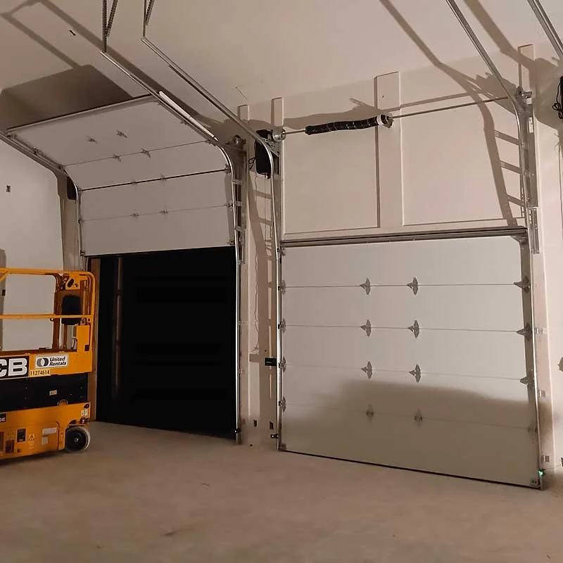 Elite Garage Door Services of Northwest Arkansas-Two overhead garage doors, one open and one closed, in a well-lit garage. A yellow lift is visible, indicating ongoing garage door service. The setting suggests professional installation or repair in Northwest Arkansas.