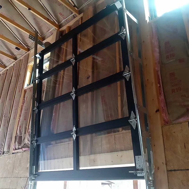 Elite Garage Door Services of Northwest Arkansas-A newly installed black-framed overhead garage door in a residential construction site, showcasing professional garage door installation in Northwest Arkansas, with insulation visible on the walls.