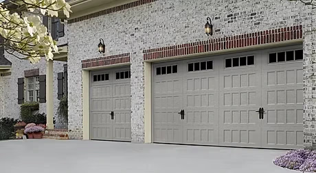 Elite Garage Door Services of Northwest ArkansasA pair of closed, light gray residential garage doors with decorative windows on a brick home in Northwest Arkansas, showcasing professional installation and reliable design suitable for local homeowners seeking quality garage door service.