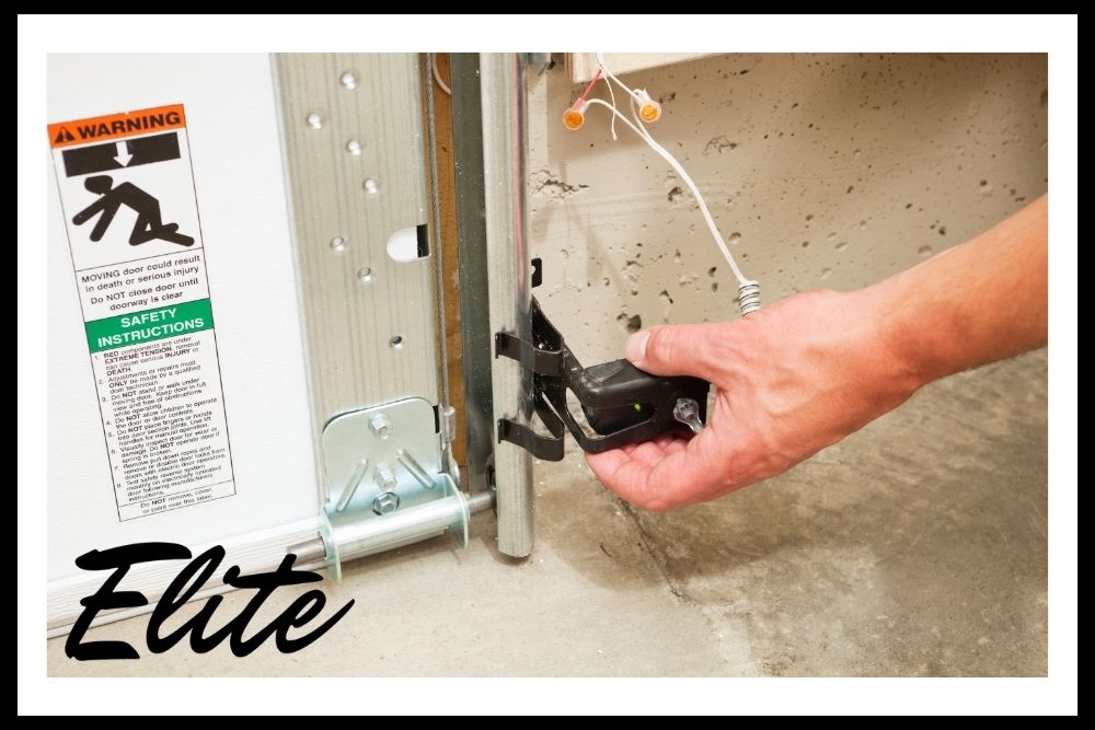 Elite Garage Door Services of Northwest Arkansas-A professional technician from Elite Garage Door in Northwest Arkansas adjusts a garage door opener sensor during a reliable garage door service, ensuring safety and efficient operation for residential overhead garage doors.