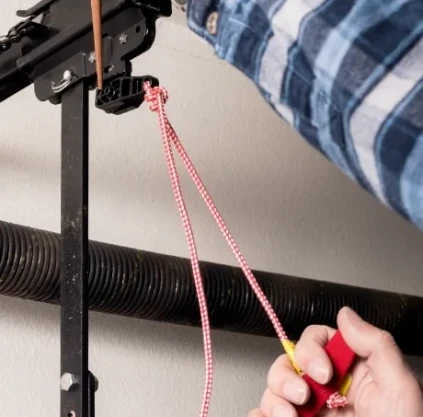 Elite Garage Door technician lubricating a torsion spring during a garage door tune-up in a Northwest Arkansas garage